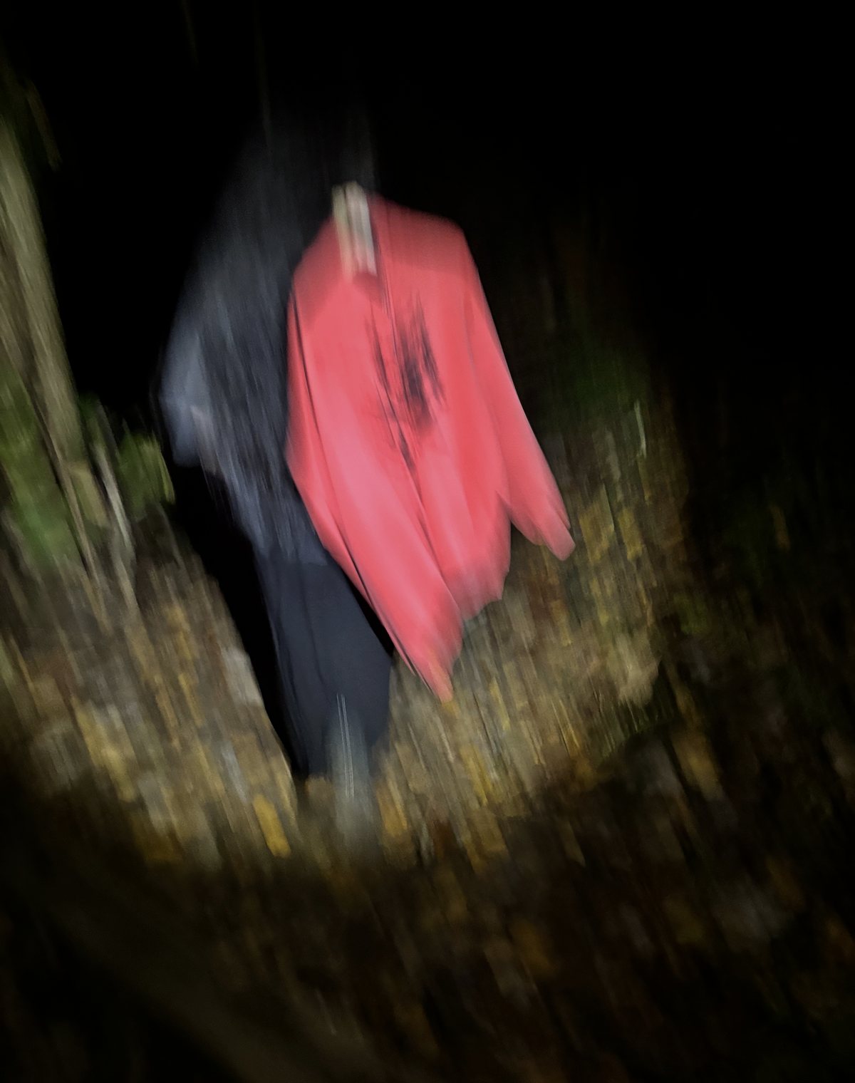 Running down a trail at night in the red Cracked Tree zip hoodie